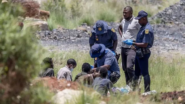 Mineros ilegales de Sudáfrica saliendo de un pozo minero