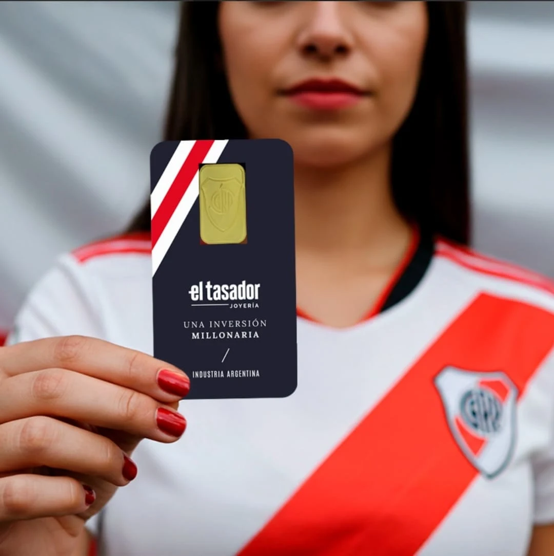Hincha de River Plate sosteniendo un lingote de oro oficial del club
