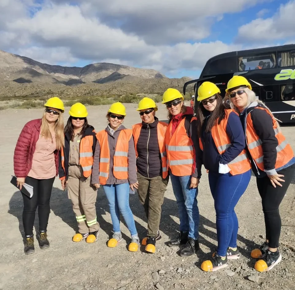 Grupo de estudiantes con cascos y chalecos de seguridad en un terreno montañoso durante una práctica de campo de Impacto ASE.