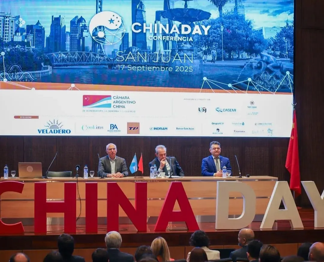 Oradores en el escenario durante el panel de apertura del China Day en San Juan, con banderas de Argentina y China de fondo.