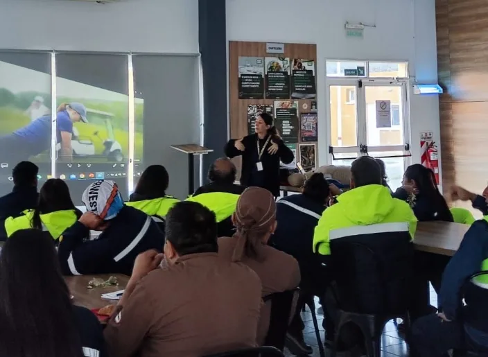 Instructores de Clínica El Castaño realizando una demostración de reanimación cardiopulmonar sobre un maniquí frente al personal de Caterwest.