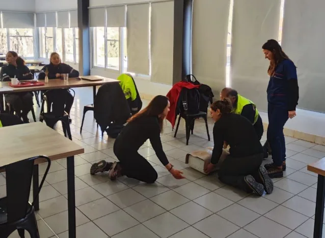 Trabajador minero arrodillado mientras practica RCP en un maniquí durante la formación en Mina Gualcamayo.