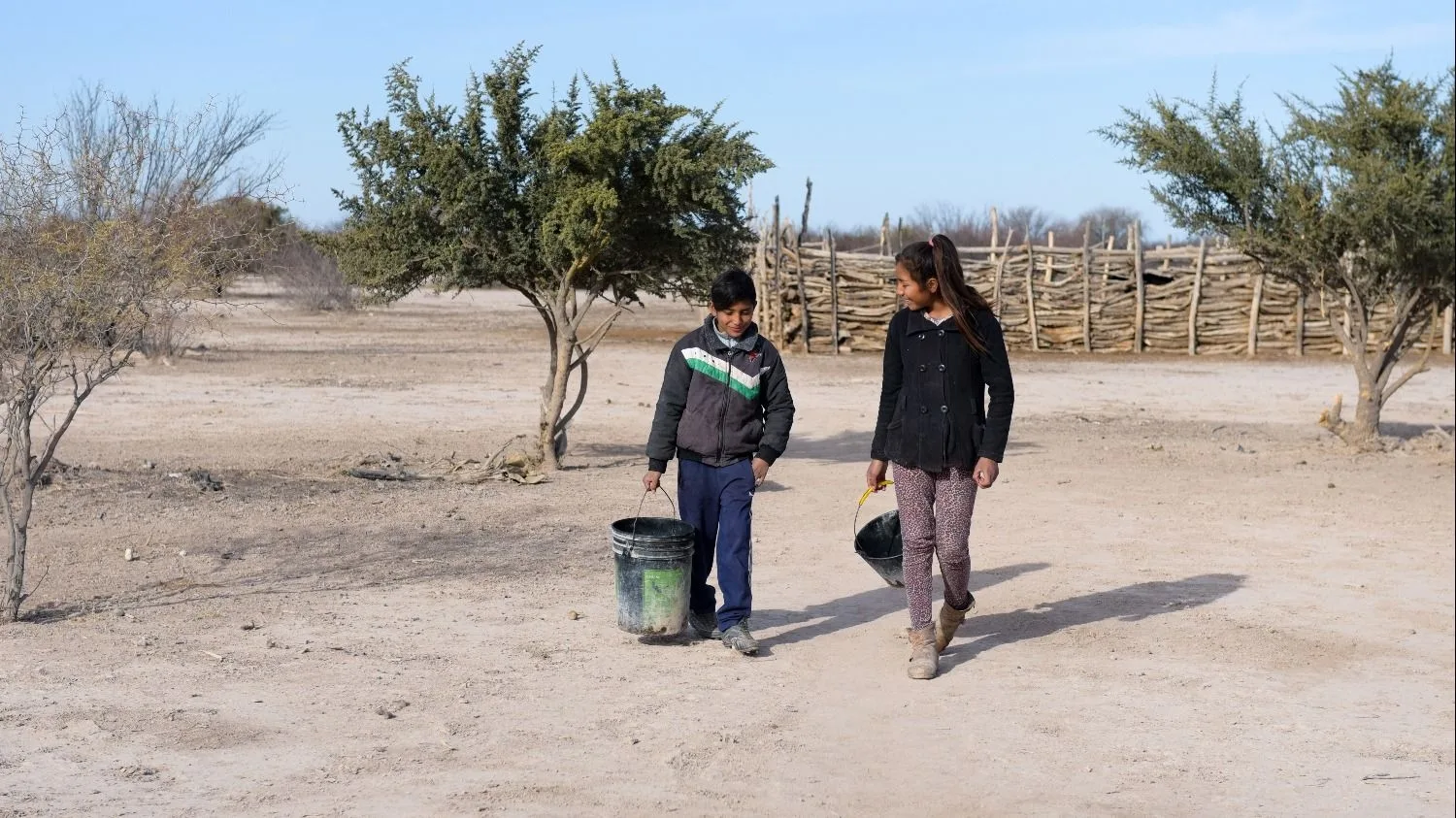 Niños llevando baldes para recolectar agua en una zona rural de San Juan