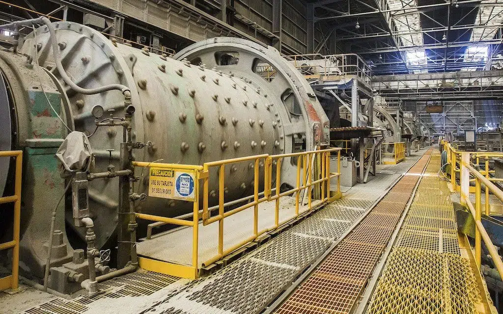 Planta industrial de procesamiento de minerales con grandes estructuras y tuberías.