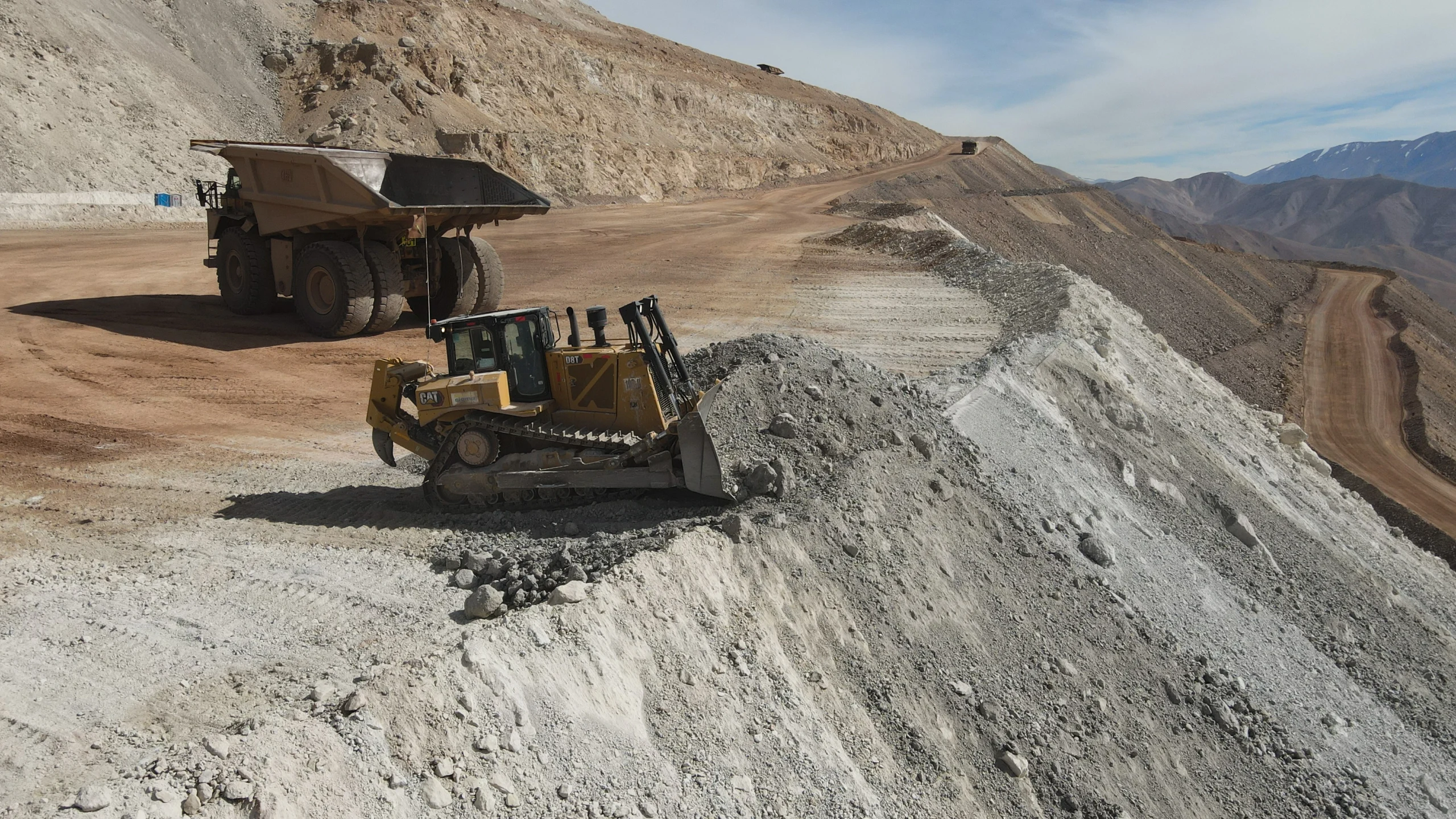 Camiones y excavadoras de la constructora MAPAL trabajando en un camino de alta montaña para la minería.