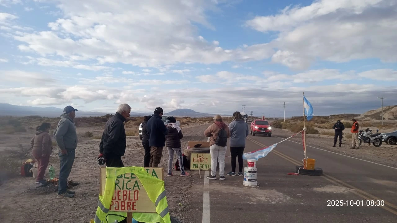 Grupo de manifestantes en una ruta de San Juan sosteniendo banderas de Argentina durante una protesta por regalías mineras.