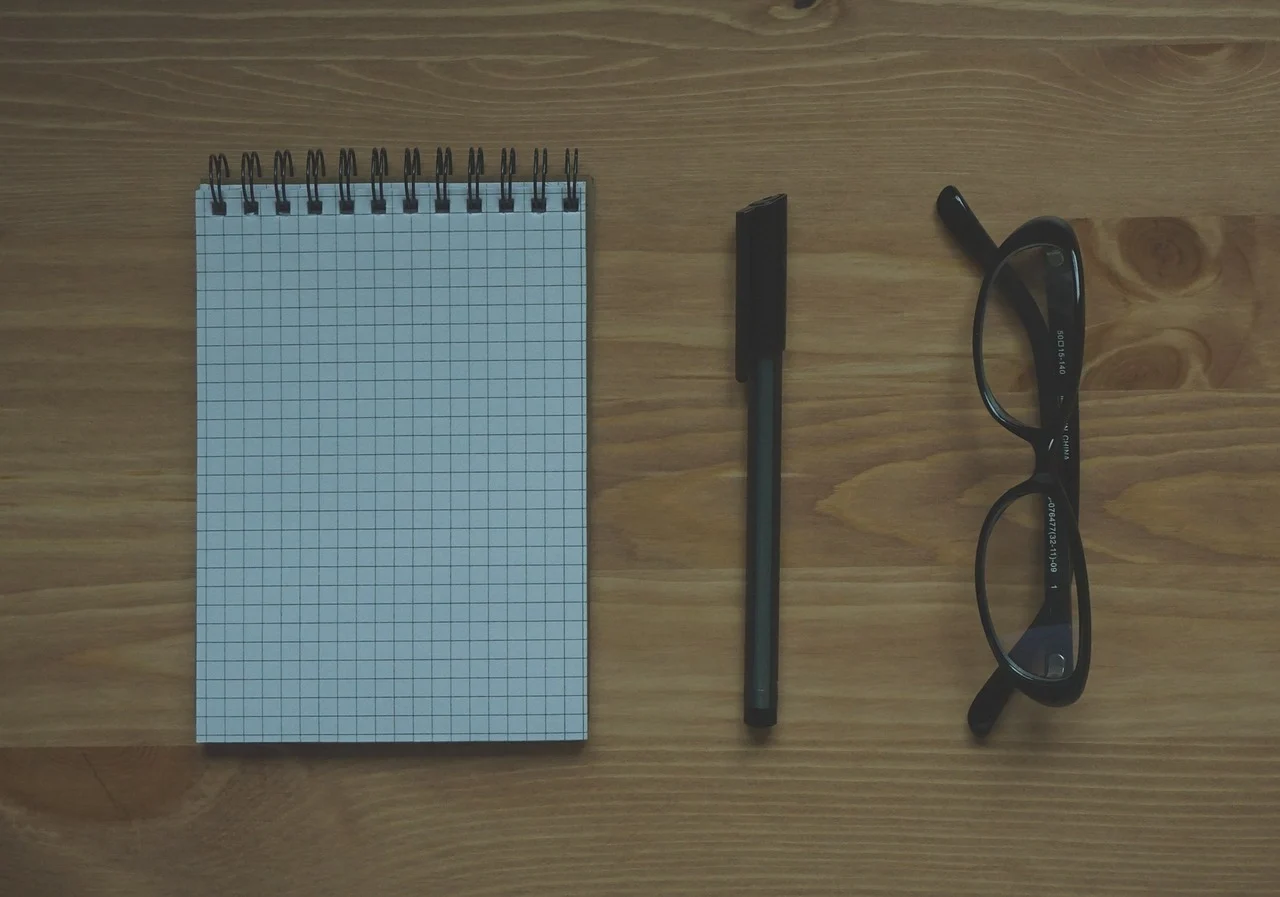 Cuaderno con unos anteojos y una lapicera, simbolizando tomar nota.