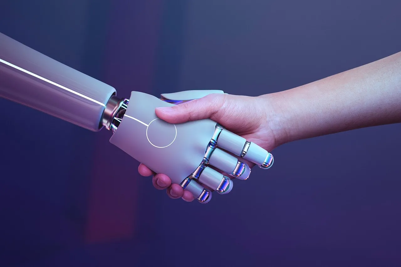 Mano robótica unida a una mano humana, simbolizando la unificación de la IA y las personas.