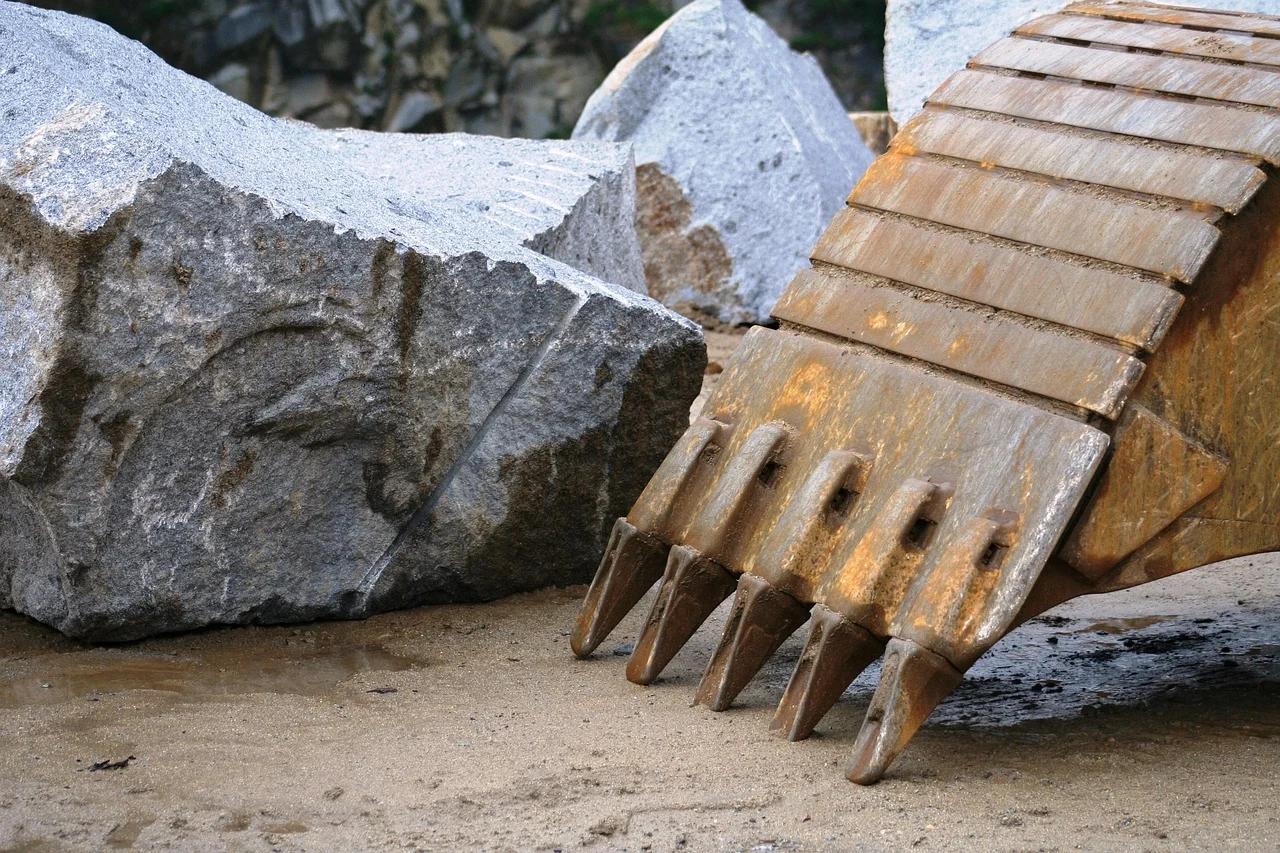 Imagen de una roca y una pala mecánica de una retroexcavadora