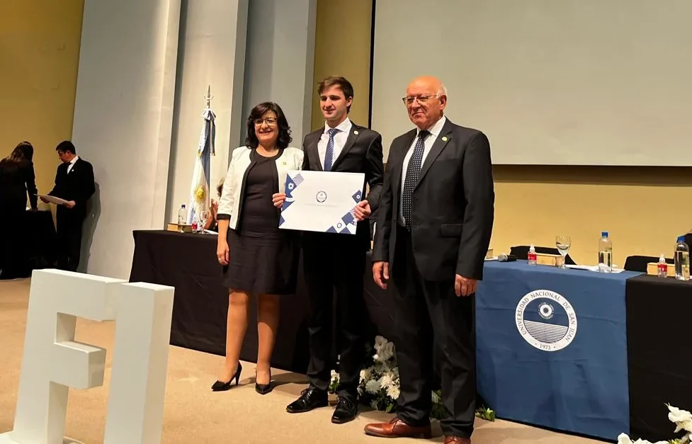 El rector de la UNSJ, Tadeo Berenguer, posa junto a un nuevo ingeniero y la decana Andrea Díaz en la ceremonia de graduación.