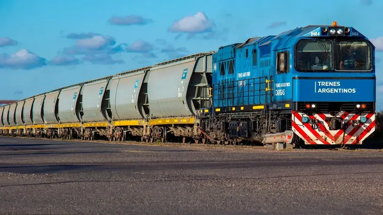Un tren de carga de la línea Belgrano Cargas avanzando por las vías en una zona árida, representando la logística minera.