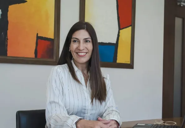 Retrato de Anabel Recabarren, mujer sonriente en un entorno de oficina, representando a una asesora financiera.