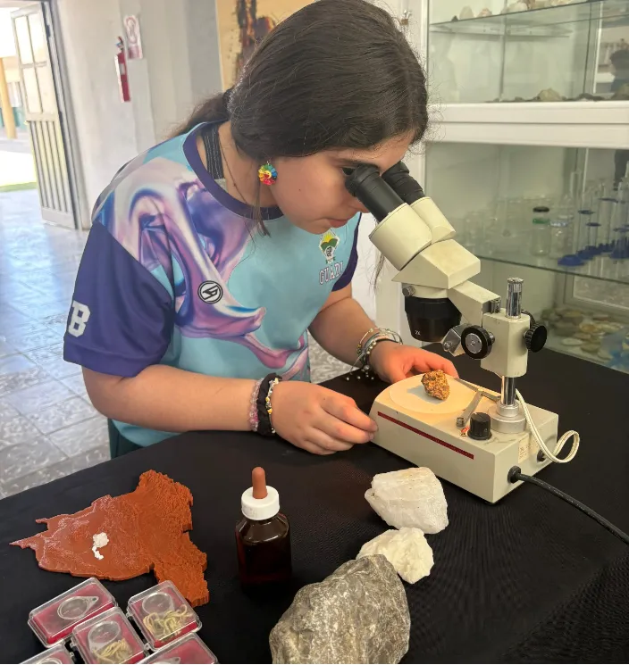 Estudiantes interactuando con muestras de minerales y equipos de laboratorio en una mesa, parte del proyecto CAL-LAB.