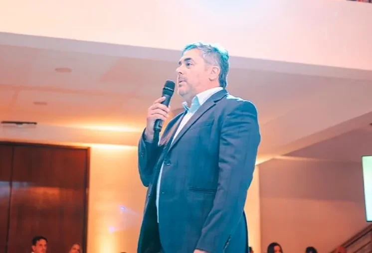  Fernando Godoy hablando desde un escenario con un micrófono, dirigiéndose a una audiencia, en la Noche CAPRIMSA.