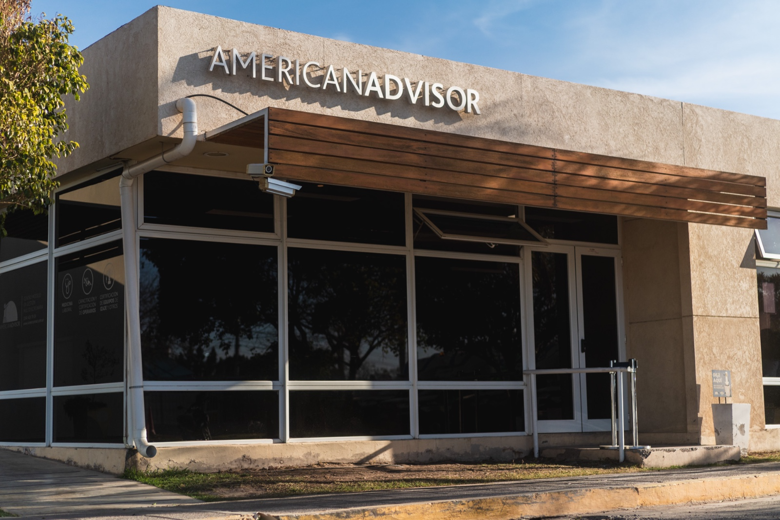 Fachada moderna de un edificio con el logo de American Advisor, que representa un centro médico y de capacitación.