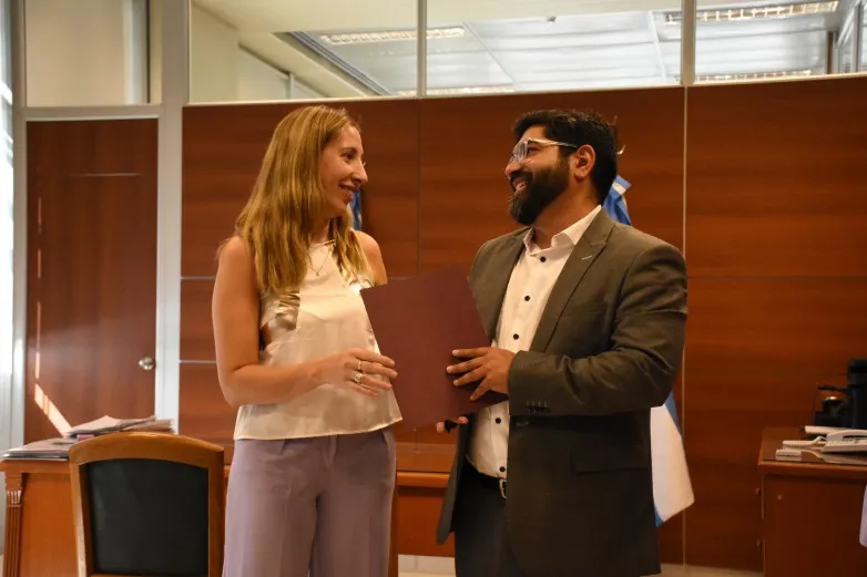 Laura Palma, ministra de San Juan, y Galo Luna Penna, delegado chileno, firmando un documento en una reunión oficial.