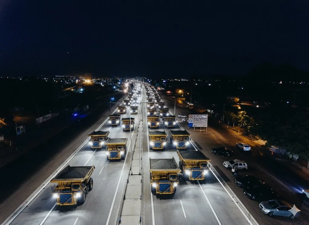 Imagen simulada de camiones de carga minera transitando por una ruta de tierra en condiciones desafiantes.