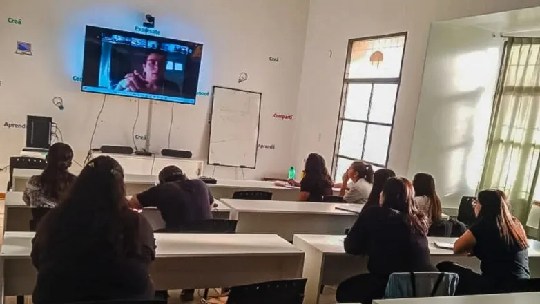 Aula híbrida universitaria con pantallas interactivas, cámaras de videoconferencia y computadoras para educación a distancia.