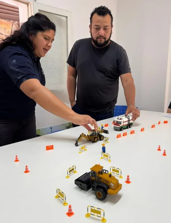 Trabajadores utilizando bloques LEGO para simular escenarios de riesgo en la capacitación de seguridad minera