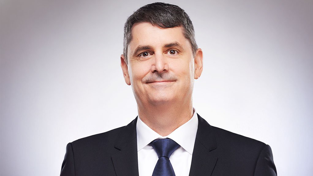 Retrato de Mark Hill, CEO de Barrick Mining Corporation, vistiendo traje formal en un entorno corporativo.