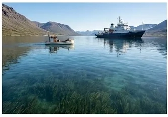 Contenido Original de ACERO Y ROCA - Prohibida su reproducción Fiordo de aguas cristalinas con embarcaciones locales. Imagen ilustrativa de Acero y Roca.