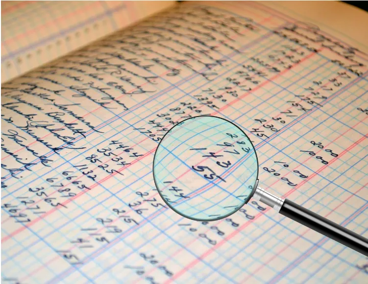 Primer plano de hoja con datos numéricos contables y lupa para revisión técnica en Auditoría Ley 24.196 Minería.