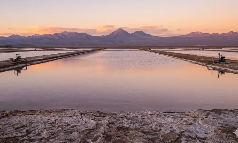 Contenido Original de ACERO Y ROCA - Prohibida su reproducción Pozas de evaporación de litio en el Salar de Atacama durante el atardecer, epicentro del Triángulo del Litio. Imagen ilustrativa de Acero y Roca.