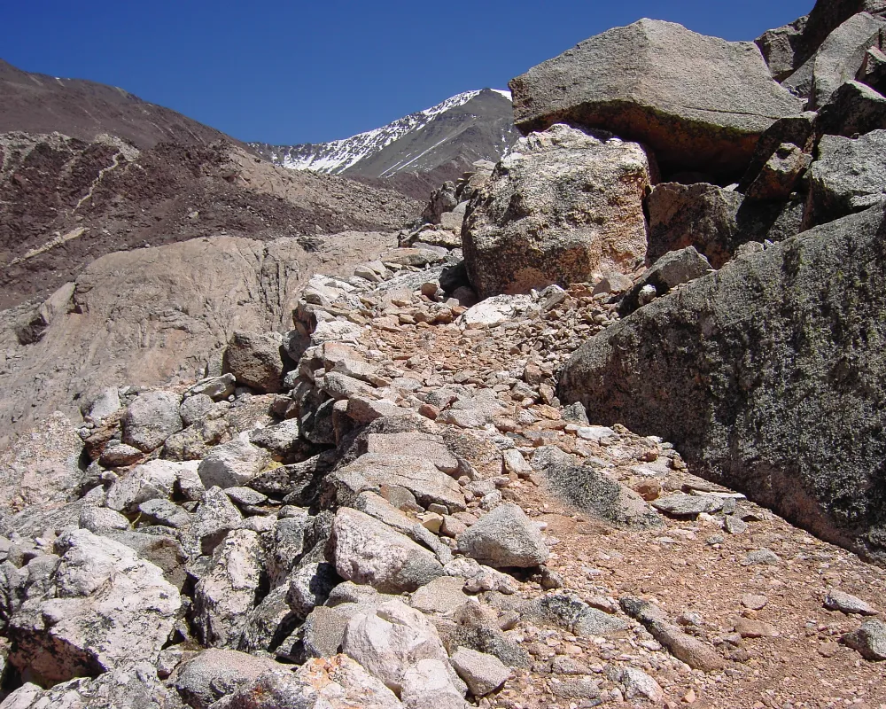 Paisaje de alta montaña en los Andes con restos de estructuras arqueológicas de altura.