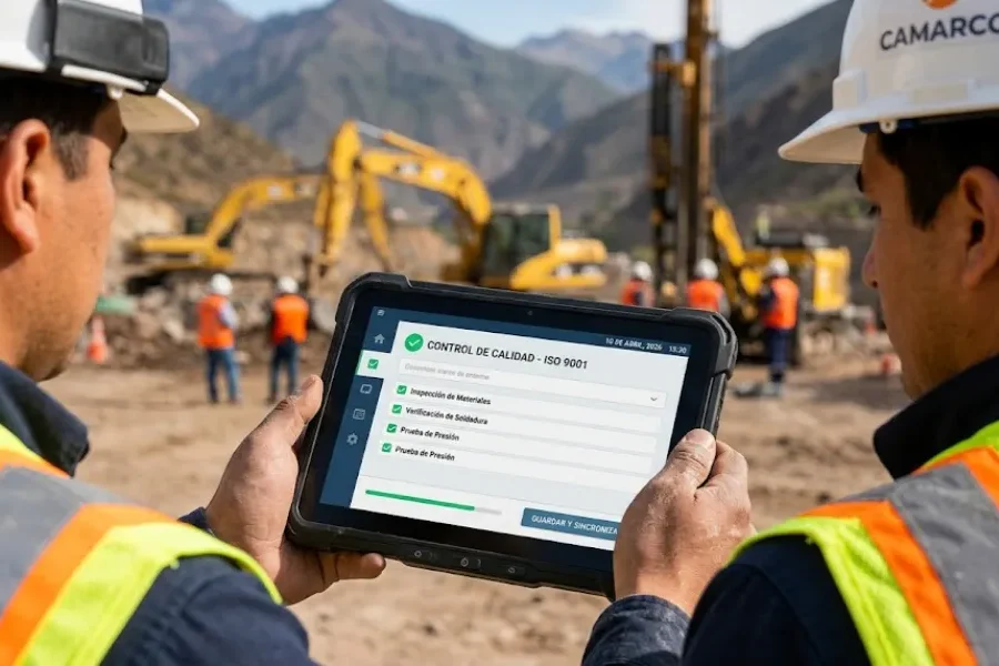 Tableta industrial resistente que muestra una aplicación de gestión de procesos limpia, sostenida por una persona con chaleco de seguridad y casco en un sitio de construcción en las montañas de San Juan. Contenido Original de ACERO Y ROCA - Prohibida su reproducción