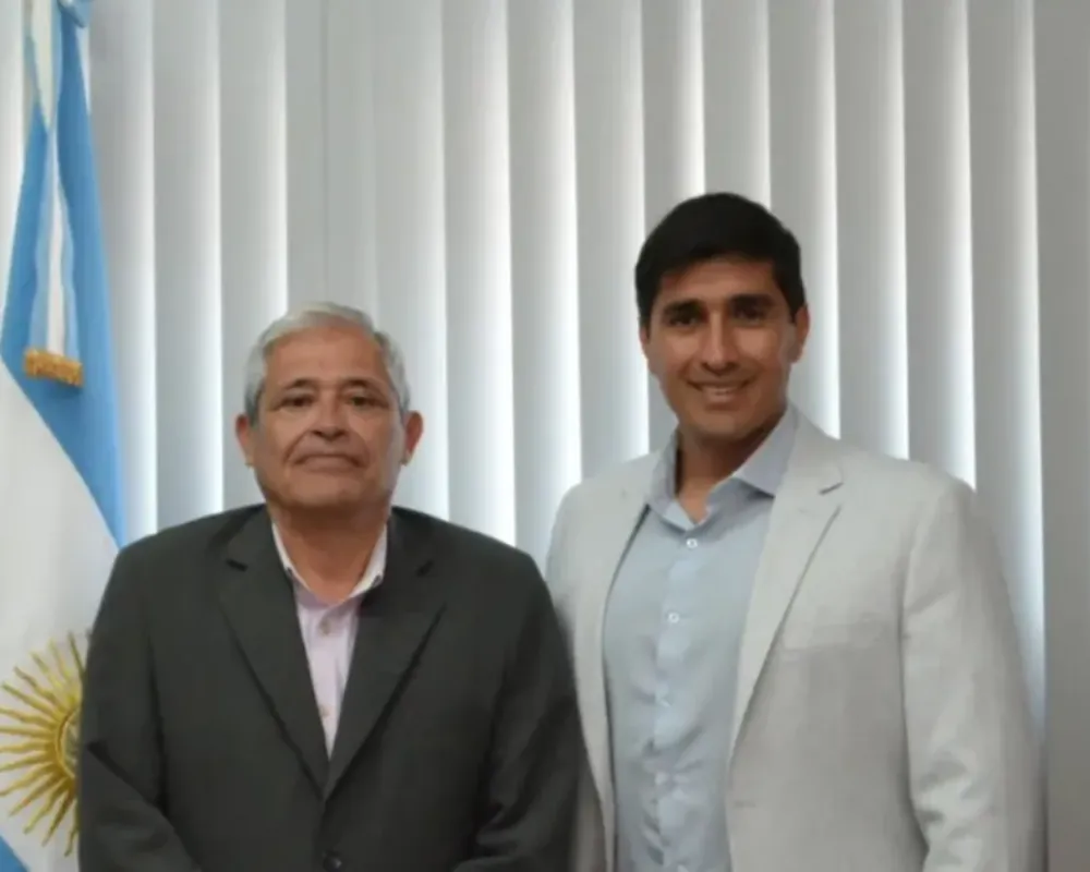 Retrato de julio davila junto a sebastian carbajal con una bandera argentina de fondo.