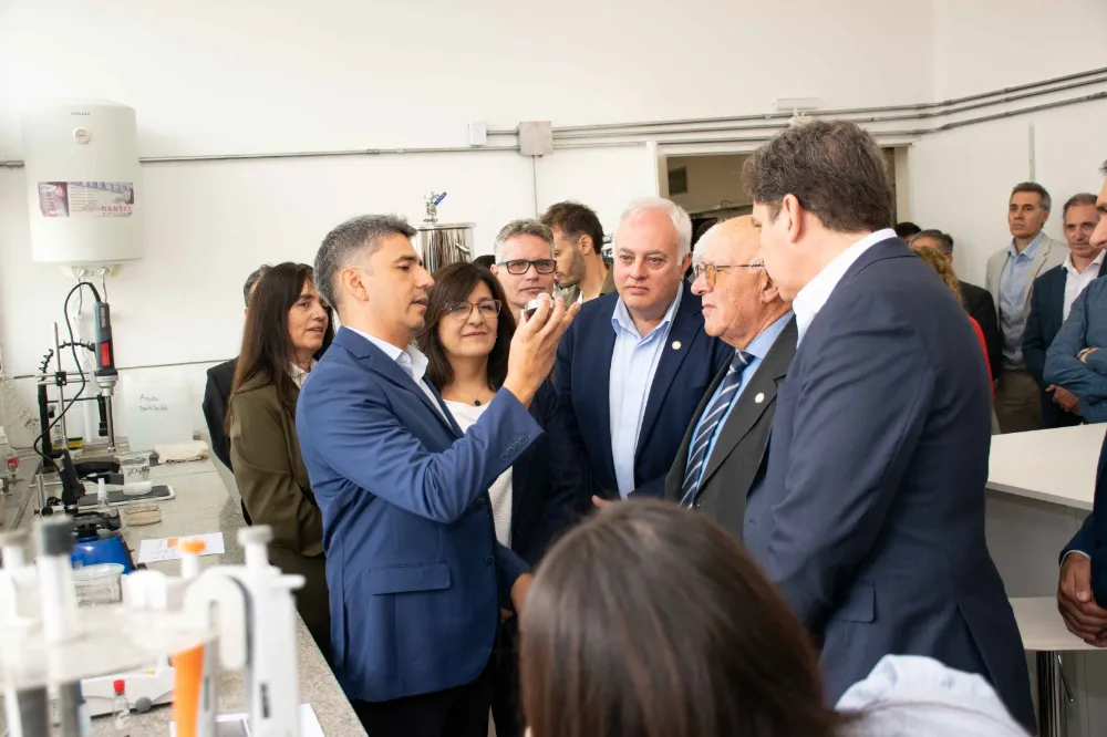 Ingeniero explica un material en laboratorio de nanotecnología ante autoridades y equipo técnico, rodeados de equipamiento científico y mesadas de trabajo en la Facultad de Ingeniería.