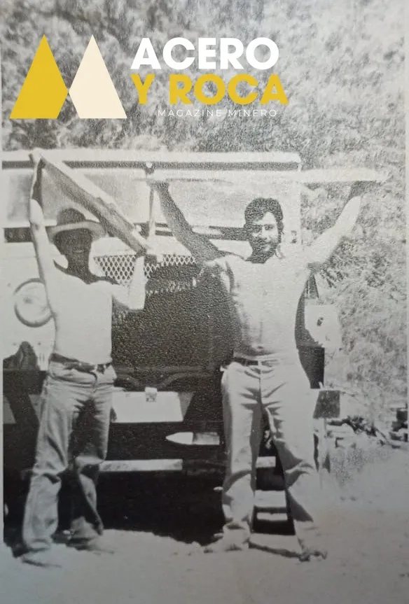 Fotografía antigua en blanco y negro de tres hombres junto a un camión de carga de gran porte en un terreno desértico.