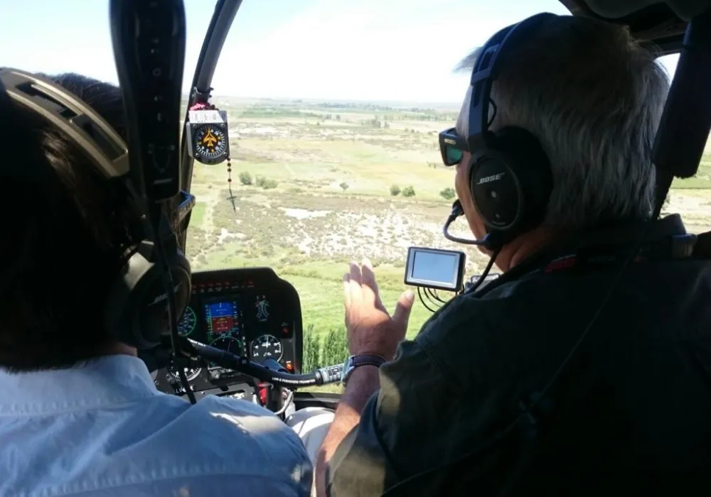 Vista desde el interior de la cabina de un helicóptero con dos pilotos trabajando.
