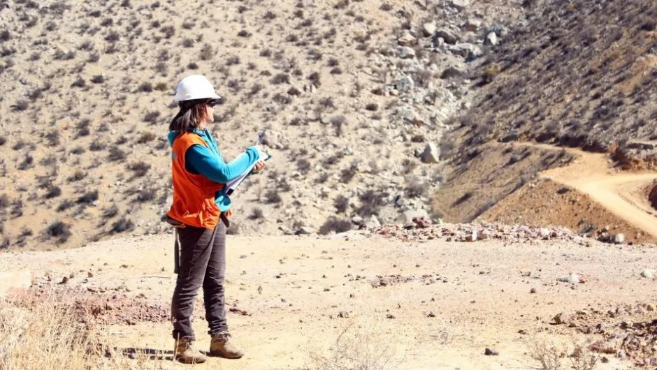 Mujer con ropa de faena, observando un paisaje montañoso.