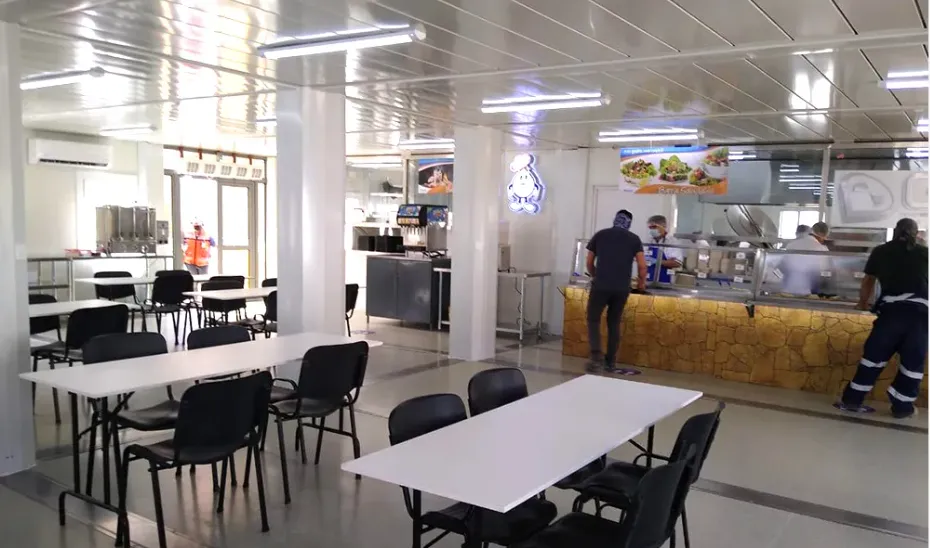Vista interna del área de comedor y distribución de alimentos en un complejo minero modular.