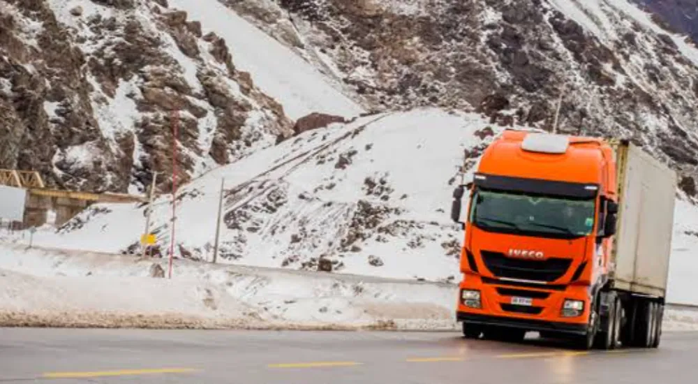 fotografia de camion minero naranja en ruta cordillerana, 