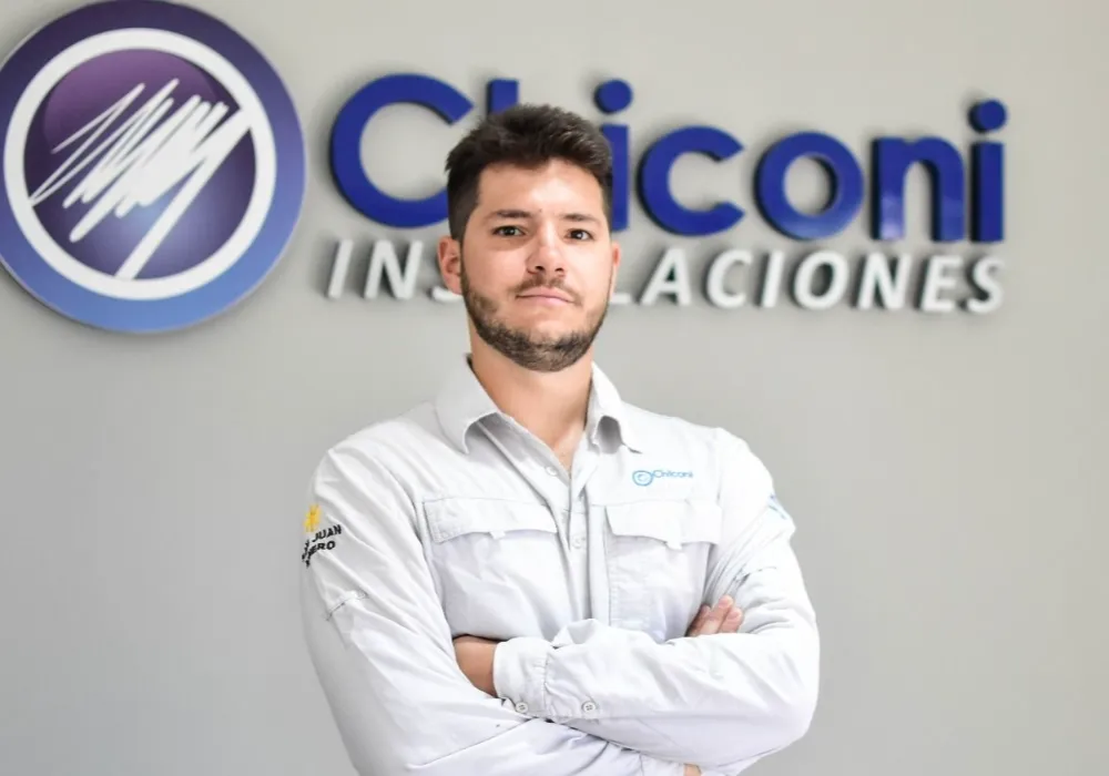 Retrato de Luciano Chiconi, empresario de Industrias Chiconi, posando con los brazos cruzados frente a un muro con el logotipo corporativo de Chiconi Instalaciones.
