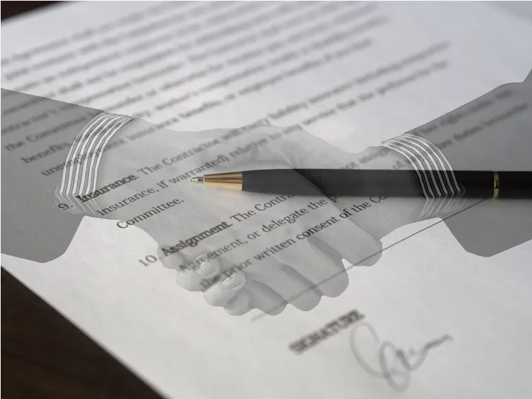 Manos estrechándose delante de unos documentos firmados.