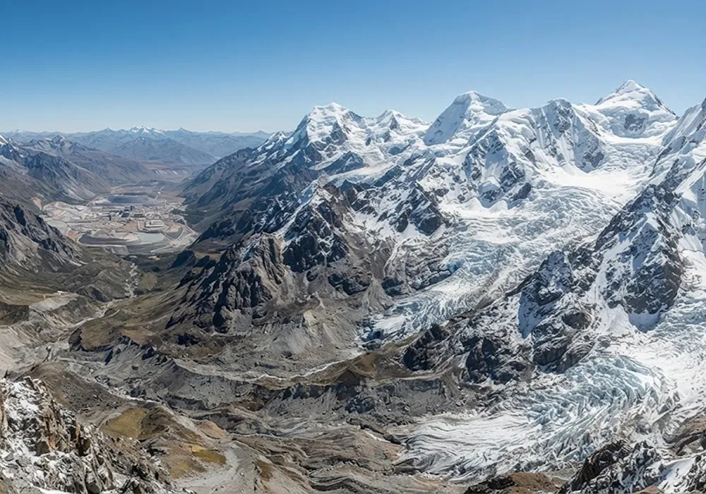 Paisaje natural prístino de glaciares y ecosistema periglacial en la alta montaña andina argentina, con un proyecto minero lejano visible en el valle.