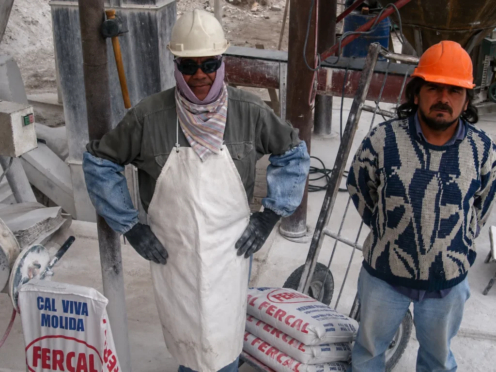 Trabajadores en una planta calera de Los Berros junto a bolsas de cal viva molida.