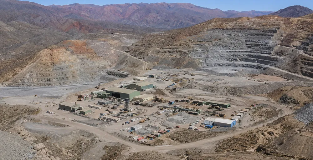 Vista exterior de la mina Gualcamayo con cartelería identificatoria de Minas Argentinas e instalaciones operativas en un entorno montañoso de San Juan.