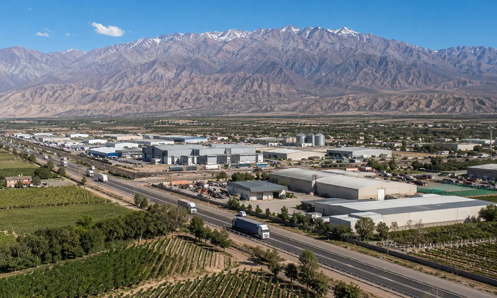 Vista panorámica de actividad industrial, logística y agroproductiva en San Juan, con transporte de cargas y cordillera de fondo.