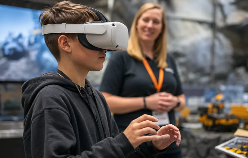 Joven utiliza un visor de realidad virtual durante una experiencia educativa relacionada con maquinaria y procesos de una operación minera.