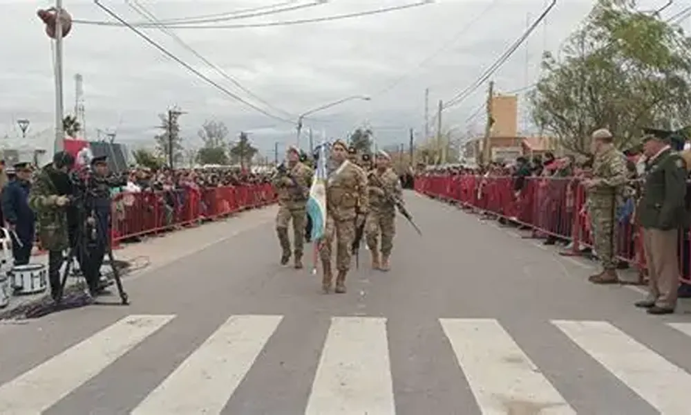 Formación de integrantes de una fuerza de seguridad durante un desfile cívico-militar sobre una avenida de Sarmiento, con público ubicado a ambos lados de la calzada.
