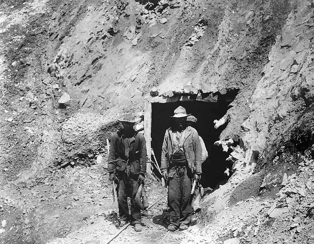 Mineros saliendo de la mina despues de la extracción de los minerales con ropas y calzados de la época
