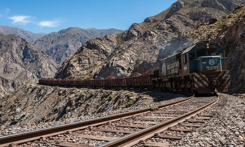 Tren de carga transportando minerales a través de un paisaje montañoso en el norte argentino.