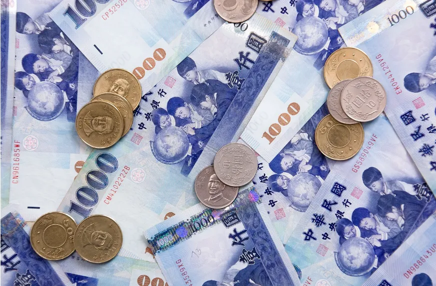 Billetes y monedas de curso legal del Nuevo Dólar Taiwanés dispuestos sobre una mesa de finanzas.
