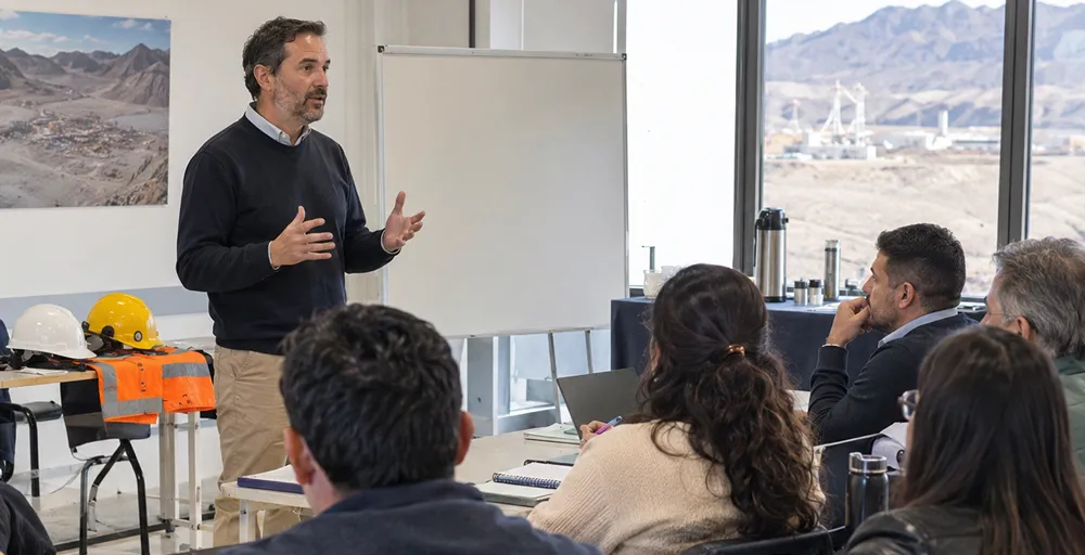 Profesionales y trabajadores analizan documentación, mapas y procesos de una operación minera durante una reunión de planificación y gestión en San Juan.