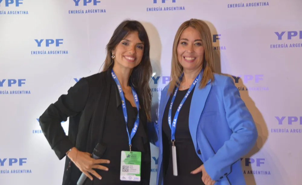 Susana Figueroa junto a otra profesional durante un encuentro del sector energético, frente a un panel institucional de YPF, en una actividad de vinculación empresarial.