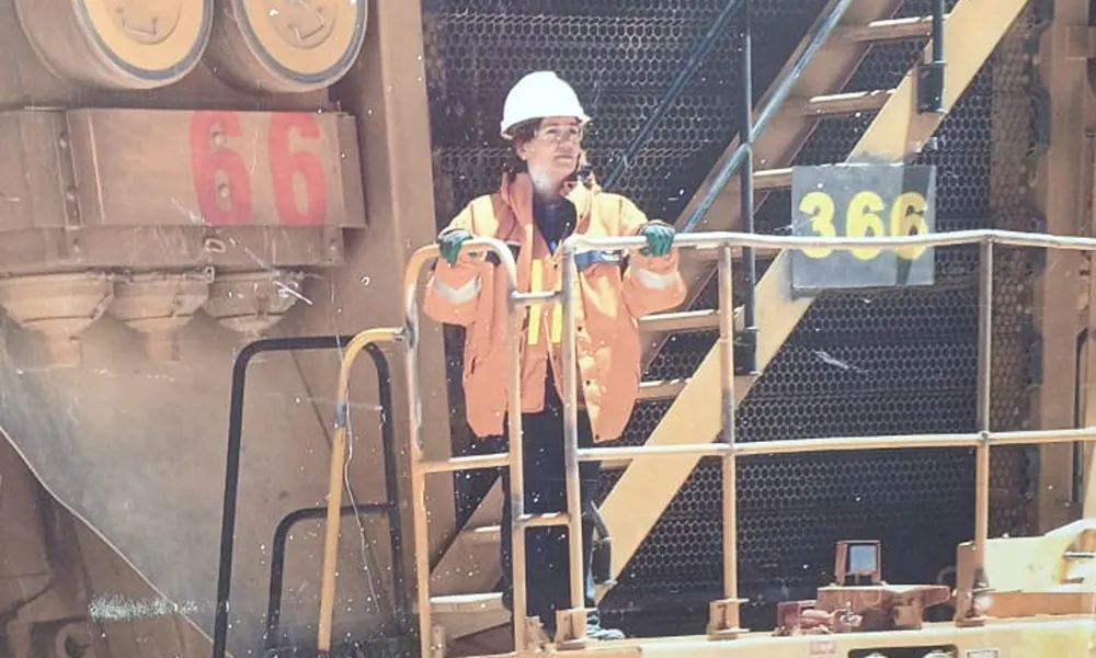 Silvana Aubone con chaleco de alta visibilidad e indumentaria de trabajo junto a maquinaria pesada en una operación minera, durante una jornada vinculada con sus tareas en Veladero.